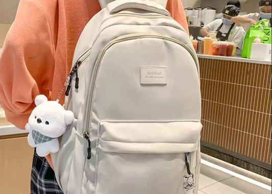 Person wearing a beige backpack with a plush toy, standing in a store.