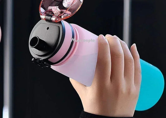 Hand holding a pink and black water bottle with a light attachment against a dark background