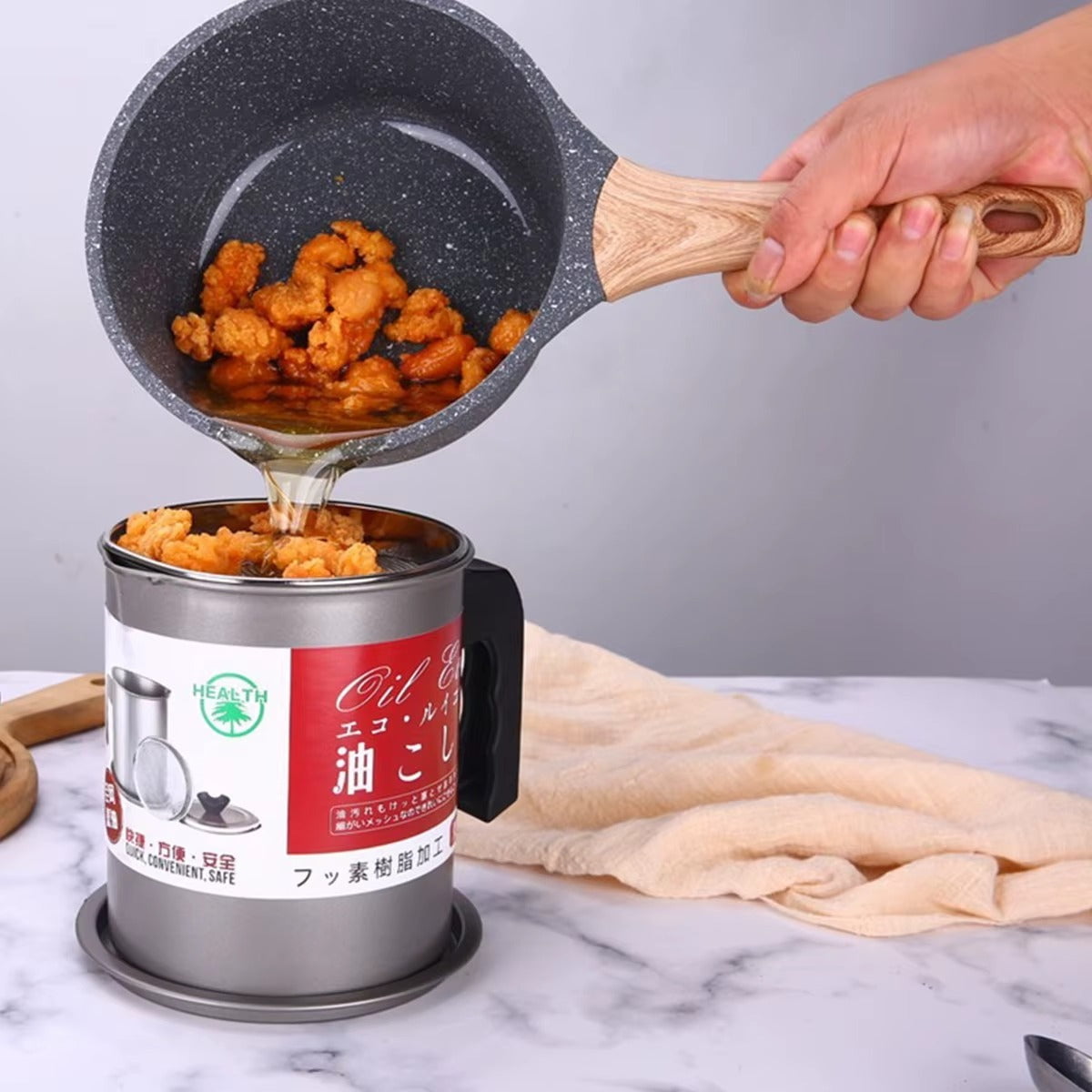 Polished stainless steel oil filter pot with a fine mesh strainer, ergonomic handle, and anti-slip base tray.